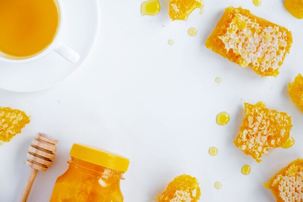 Composizione di prodotti a base di miele. Miele in barattolo, favo, tè e cucchiaio speciale. sfondo bianco
