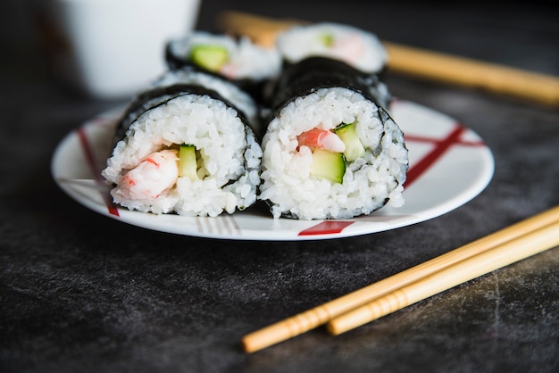 Composizione di rotoli di sushi sul piatto e bacchette