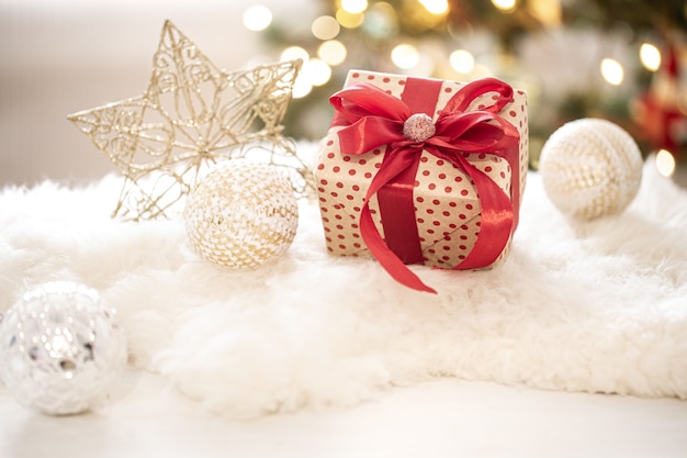 Composizione di un regalo di Natale e decorazione di Capodanno su sfondo chiaro con luci di Gerland.