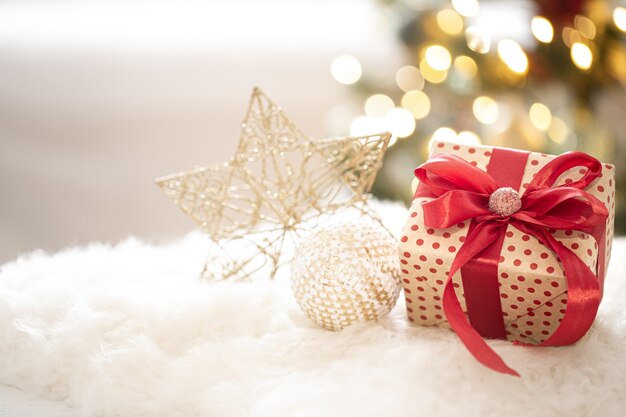Composizione di un regalo di Natale e decorazione di Capodanno su sfondo chiaro con luci di Gerland.