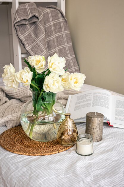 Composizione domestica con un mazzo di tulipani in un vaso di vetro e candele