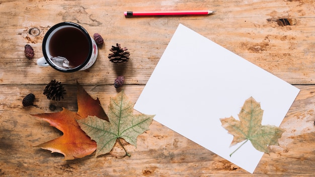 Composizione in autunno con foglie e tè su fondo in legno