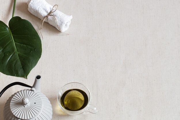 Composizione minimalista con tè verde in tazza, teiera e accessori da bagno. Concetto di salute e bellezza.