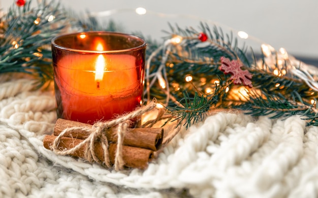 Composizione natalizia con candela e bastoncini di cannella su sfondo sfocato