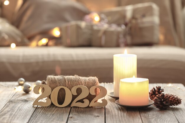 Composizione natalizia domestica con numeri decorativi in legno 2022, candele e dettagli decorativi su uno sfondo interno sfocato della stanza.