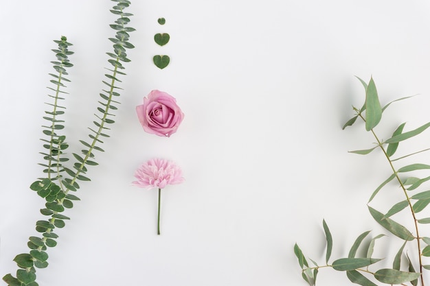 composizione naturale con due fiori rosa e cuori floreali