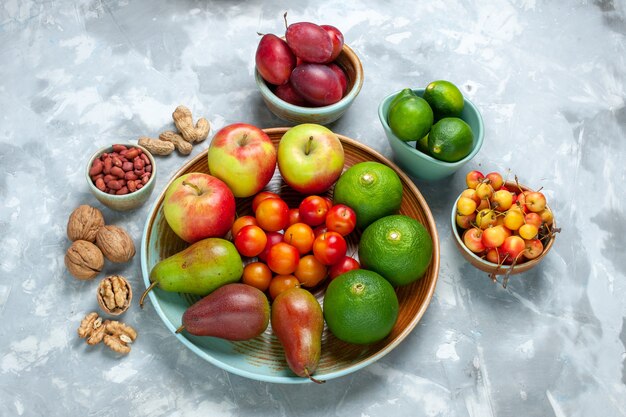 Composizione nella frutta con vista dall'alto, mele, pere, mandarini e prugne sullo scrittorio bianco.