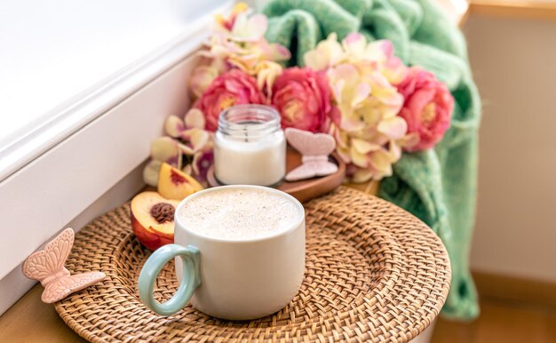 Composizione per la casa con una tazza di caffè fiori e un elemento in maglia