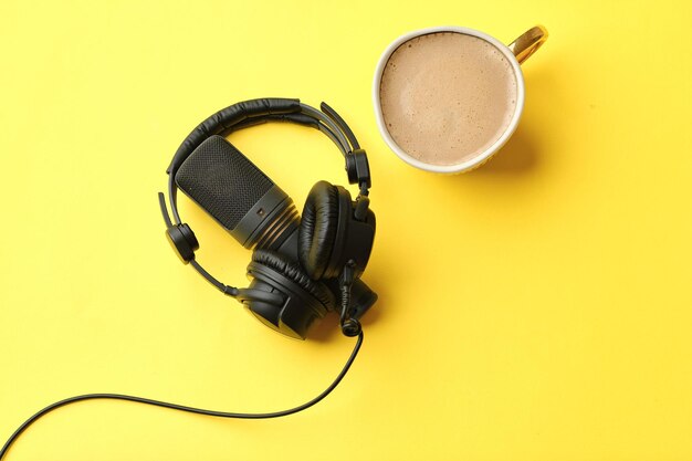 Composizione piatta con microfono per podcast e cuffie da studio nere su sfondo giallo con concetto di formazione online per l'apprendimento del caffè