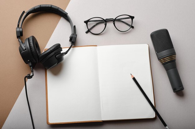Composizione piatta con microfono per podcast e cuffie da studio nere su sfondo marrone con caffè e laptop per l'apprendimento online concettoxA