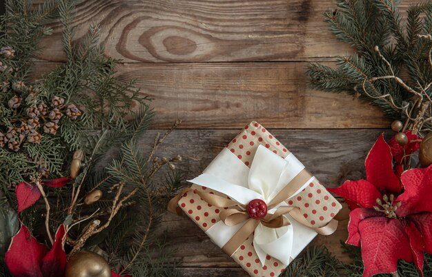 Composizione piatta natalizia con fiori di poinsettia e regalo di Natale su fondo di legno.