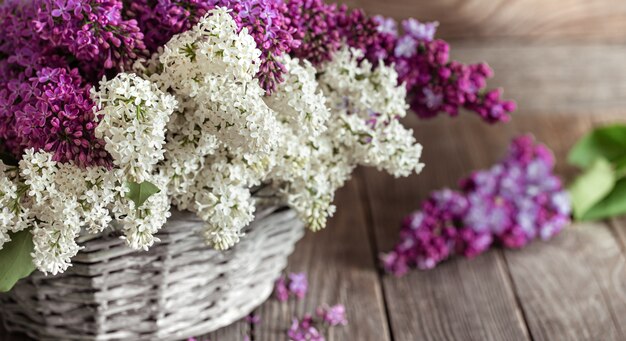 Composizione primaverile con fiori lilla in cesto di vimini. Festa della mamma e della donna. Spazio per il testo. Orientamento orizzontale. Cesti regalo e consegne di fiori