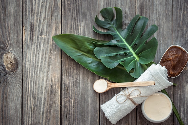 Composizione spa con asciugamani e foglia tropicale su una parete in legno.