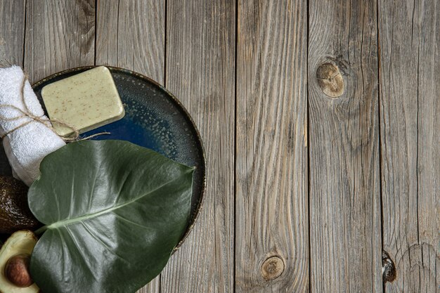 Composizione Spa con sapone, avocado, asciugamano e foglia sulla superficie in legno copia spazio.