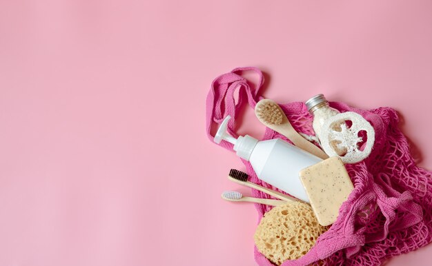 Composizione spa piatta con articoli per l'igiene personale e accessori da bagno in una borsa a tracolla.