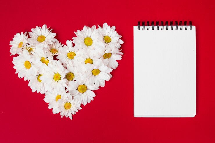Foto gratuito composto a forma di cuore di fiori e blocco note