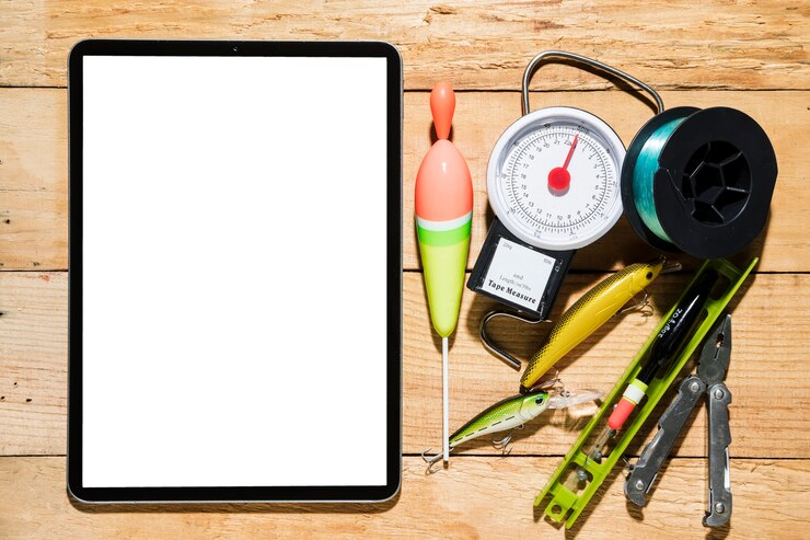 Foto gratuito compressa digitale dello schermo in bianco con attrezzatura per la pesca sullo scrittorio di legno