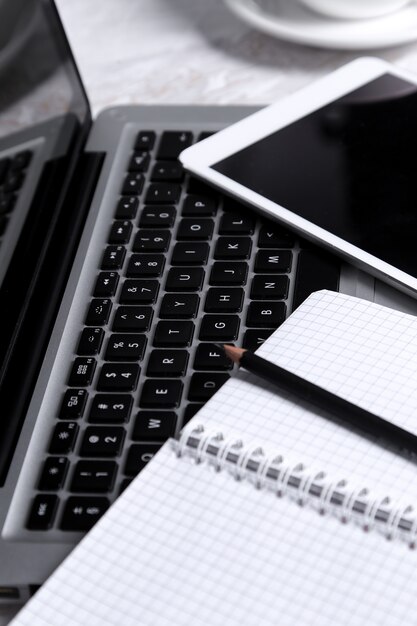 Computer portatile, blocco note e penna sul tavolo