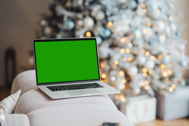 Computer portatile con chromakey schermo verde vicino a tema natalizio di decorazioni di capodanno