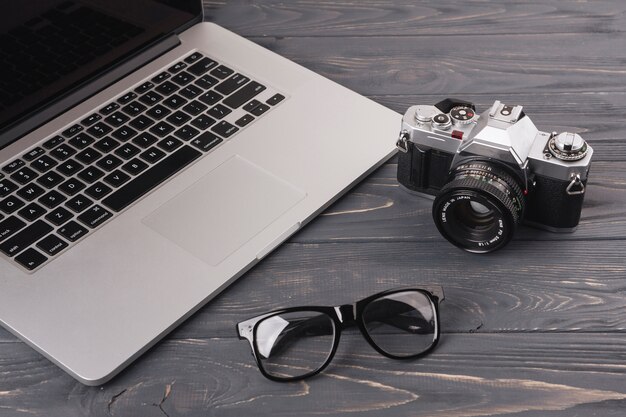 Computer portatile con fotocamera e bicchieri sul tavolo