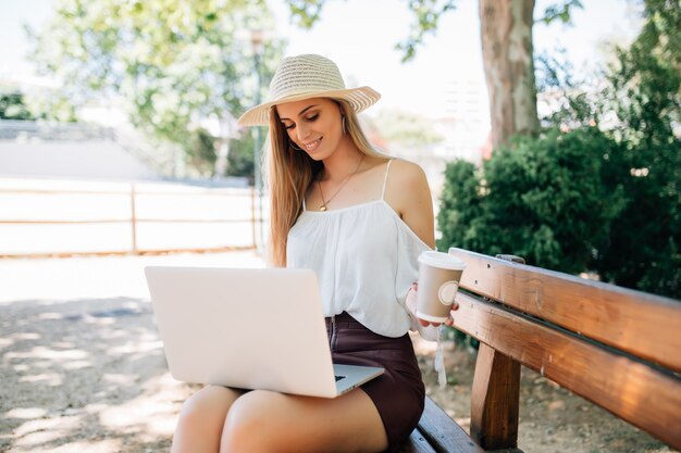 Computer portatile della giovane donna graziosa nel parco.