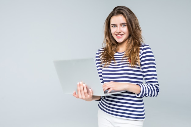 Computer portatile della tenuta della giovane donna su fondo bianco