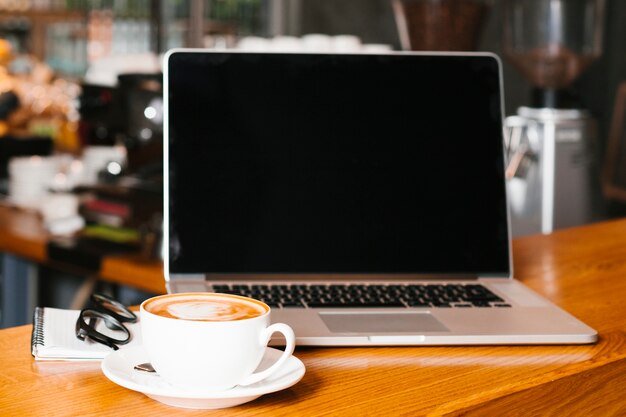 Computer portatile e caffè di Frontview su superficie di legno