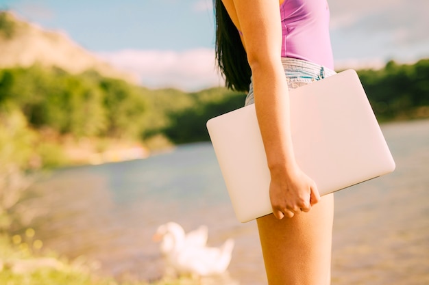 Computer portatile femminile irriconoscibile della tenuta nel posto pittoresco