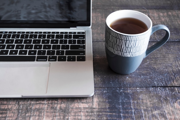 Computer portatile grigio con caffè sulla tavola di legno