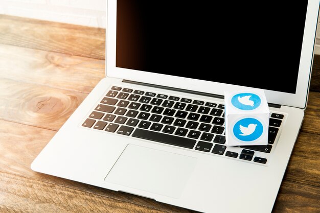 Computer portatile in bianco con scatola dell&#39;icona di twitter sul banco di lavoro