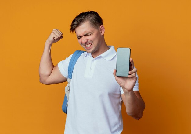 Con gli occhi chiusi gioiosa giovane studente maschio bello che indossa il telefono azienda borsa posteriore