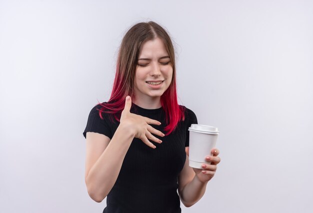 Con gli occhi chiusi giovane bella ragazza che indossa la maglietta nera che tiene tazza di caffè sulla parete bianca isolata