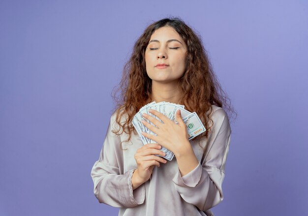 Con gli occhi chiusi ha impressionato la giovane ragazza graziosa che tiene soldi isolati sulla parete blu