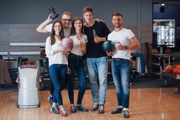 Con il fotografo. I giovani amici allegri si divertono al bowling durante i fine settimana