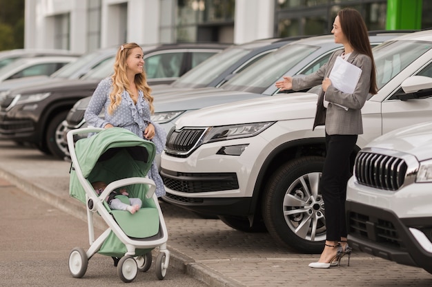 Concessionario di automobili femminile che dà il benvenuto ad un compratore