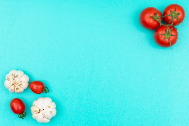 Concetto dell'aglio e dei pomodori con la vista superiore dello spazio della copia su superficie blu-chiaro
