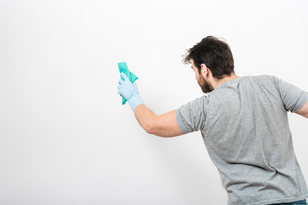 Concetto dell&#39;uomo che pulisce la sua casa con copyspace sulla parete