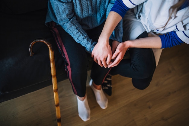 Concetto della casa di riposo con il tenersi per mano della donna e dell&#39;infermiere