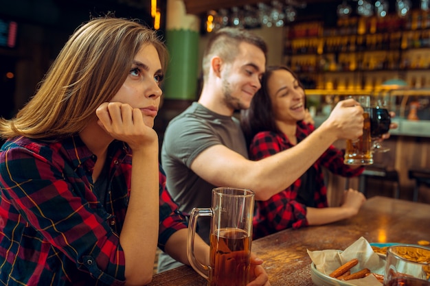 Concetto della gente, di svago, di amicizia e di comunicazione - amici felici che bevono birra, chiacchiere e tintinnio al bar o al pub