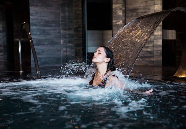 Concetto della stazione termale con la donna che si distende in acqua