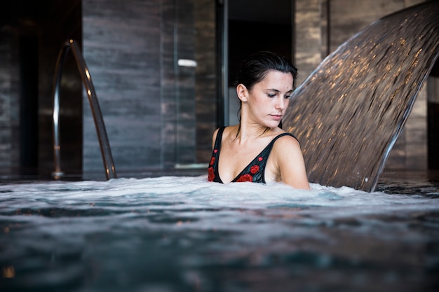 Concetto della stazione termale con la donna che si distende in acqua