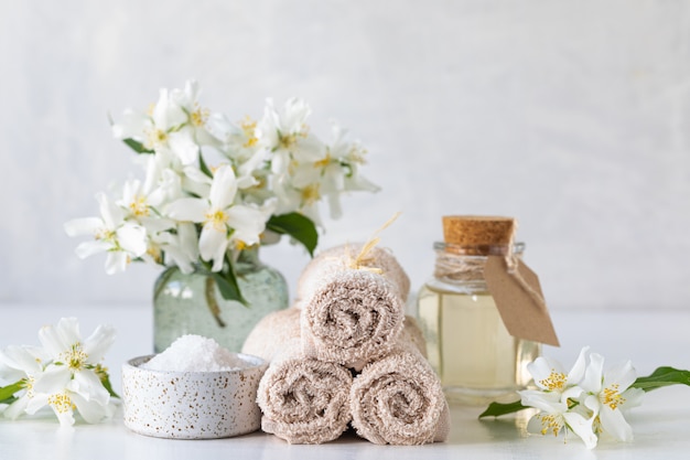 Concetto della stazione termale di olio di gelsomino, con sale da bagno e fiori