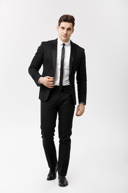 Concetto di affari: ritratto a figura intera di un elegante uomo d'affari in abito intelligente che cammina su sfondo bianco.
