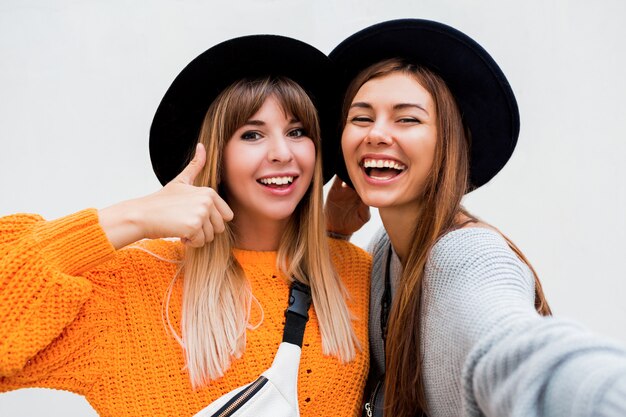 Concetto di amicizia, felicità e persone. Due ragazze sorridenti che bisbigliano gossip su bianco