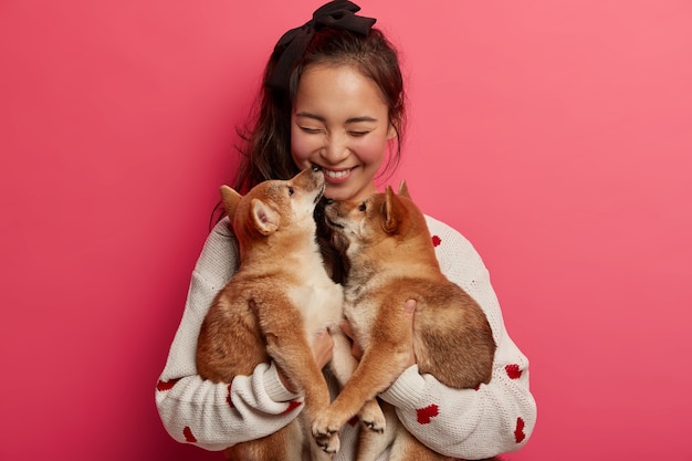 Concetto di amicizia umana e animale. Ragazza allegra felice di avere due cuccioli di razza per il suo compleanno, baci pet