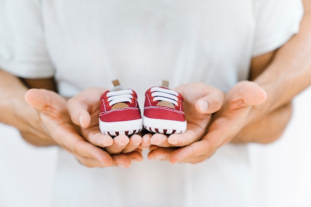 Concetto di bambino con le mani che tengono le scarpe