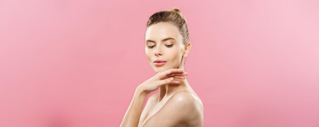 Concetto di bellezza della pelle Bella giovane donna caucasica con pelle pulita fresca distoglie lo sguardo con sfondo rosa studio Ragazza bellezza cura del viso Trattamento viso Cosmetologia bellezza e spa