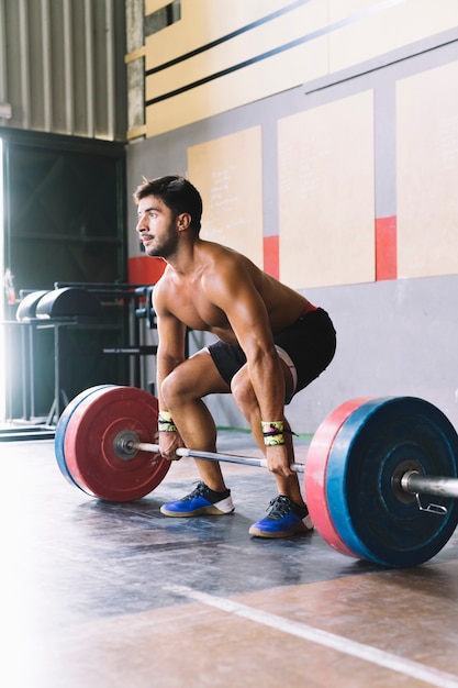 Concetto di bodybuilding con l&#39;uomo che lavora con barbell