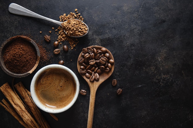 Concetto di caffè con diversi tipi di caffè caffè in grani latte e bastoncini di cannella su sfondo grigio Piatto