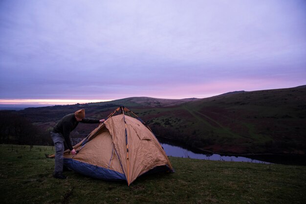Concetto di campeggio invernale con l'uomo che monta la tenda